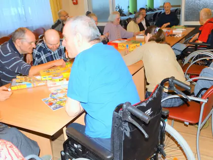 Mieszkańcy grają przy stołach w świetlicy