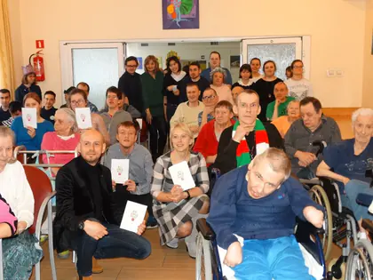 Mieszkańcy i kolędnicy z kartkami pozują w świetlicy
