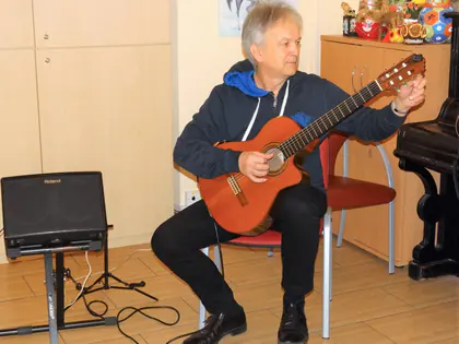 Gitarzysta gra na gitarze klasycznej w świetlicy obok wzmacniacza