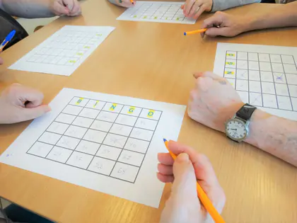Dłonie z długopisami nad kartami do gry w bingo na stole