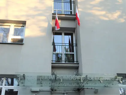 Fasada budynku z napisem Dom Pomocy Społecznej Warszawa ul. Wójtowska, w oknach biało-czerwone flagi