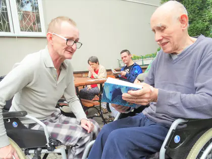 Mieszkańcy na wózkach przeglądają książki z fotografiami