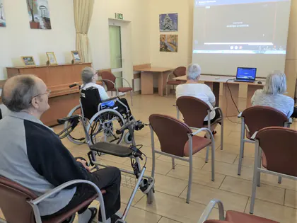Mieszkańcy siedzą przed ekranem z transmisją warsztatów