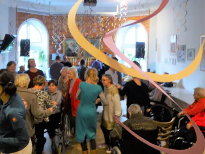 Mieszkańcy i goście tańczą na balu karnawałowym w sali ozdobionej serpentynami