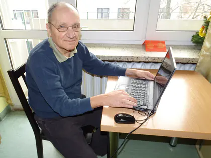 Mieszkaniec pracuje na laptopie przy biurku pod oknem