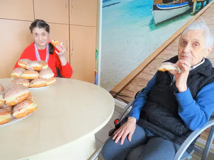 Dwie mieszkanki jedzą pączki przy okrągłym stole