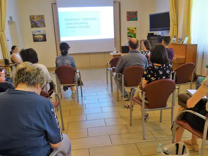 Mieszkańcy słuchają szkolenia przed ekranem z prezentacją