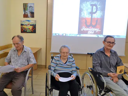 Mieszkańcy czytają teksty przed ekranem ze znakiem Polski Walczącej i napisem Pamiętamy 1944