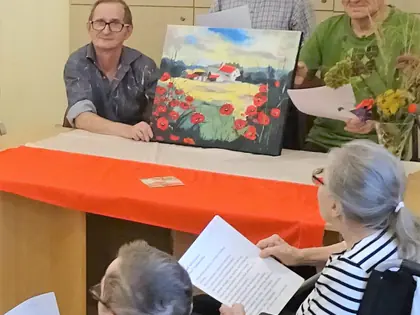 Mieszkańcy przy stole z obrazem przedstawiającym maki