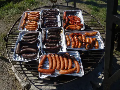 Kiełbaski i kaszanki w tackach na ruszcie nad ogniskiem