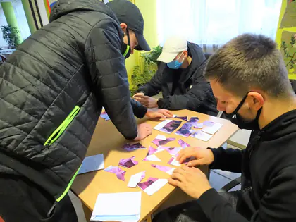 Młodzież układa puzzle ze zdjęć przy stole