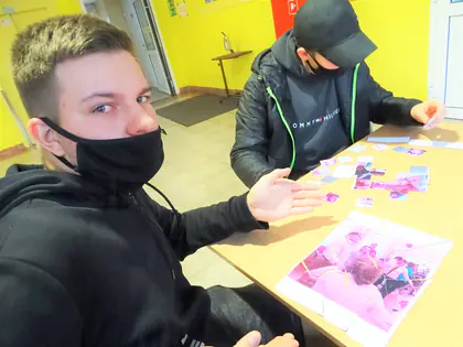 Młodzi mężczyźni układają puzzle ze zdjęć przy stole
