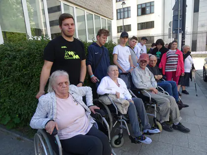 Młodzież i mieszkańcy na wózkach pozują na chodniku
