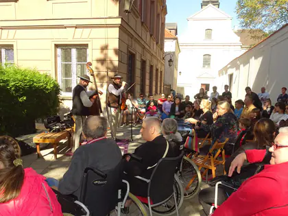 Mieszkańcy i młodzież słuchają kapeli góralskiej na dziedzińcu przed kościołem