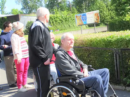 Mieszkańcy, jeden na wózku, stoją przy wejściu do ZOO