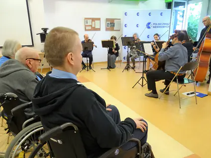 Mieszkańcy na wózkach słuchają koncertu kwartetu smyczkowego