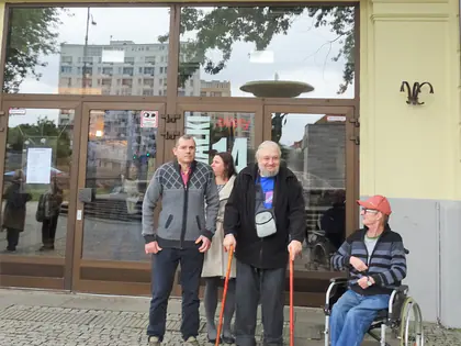 Mieszkańcy, jeden na wózku, stoją przed wejściem do kina
