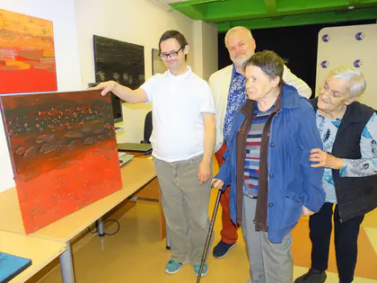 Mieszkańcy oglądają i dotykają obrazy w galerii
