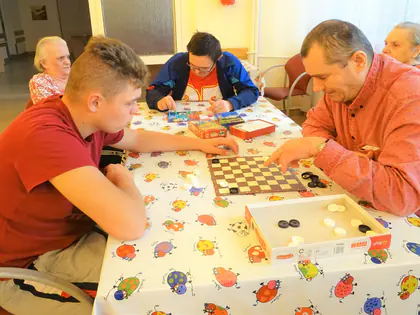 Chłopak gra w warcaby z mieszkańcem w czerwonej koszuli