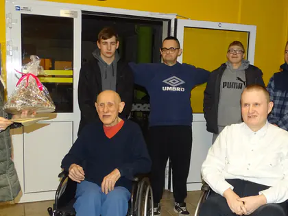 Kobieta wręcza paczkę, obok młodzież i mieszkańcy na wózkach