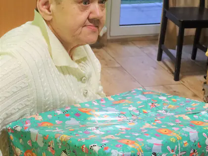 Mieszkaniec trzyma duży prezent w kolorowym papierze
