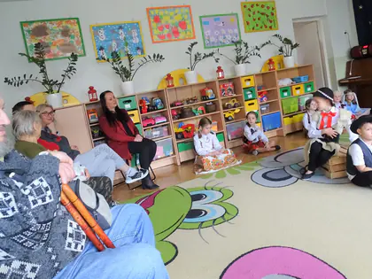 Mieszkańcy siedzą wśród dzieci w strojach podczas jasełek