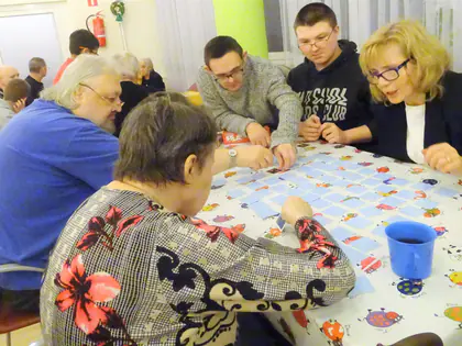 Mieszkańcy i młodzież grają w memory przy stole