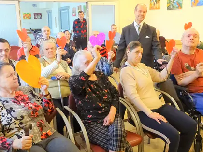 Mieszkańcy unoszą papierowe serca, obok stoi śpiewak w garniturze