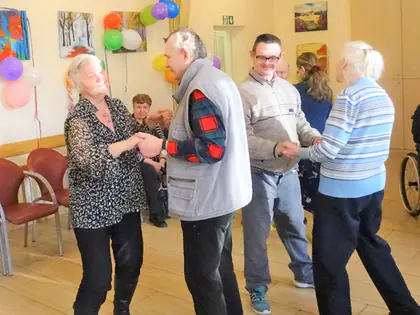 Mieszkańcy tańczą w parach w świetlicy z balonami