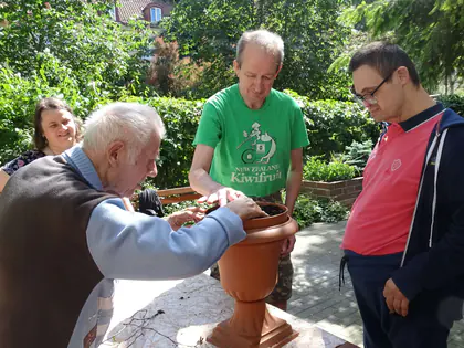 Mieszkańcy sadzą rośliny w dużej donicy w ogrodzie