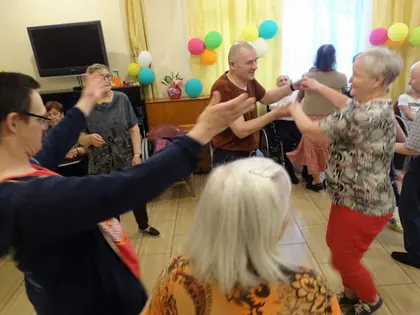 Mieszkańcy i goście tańczą w sali ozdobionej kolorowymi balonami