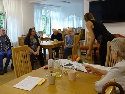 Mieszkańcy śpiewają przy stolikach z prowadzącą