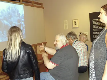 Mieszkańcy oglądają film na ekranie w sali muzealnej