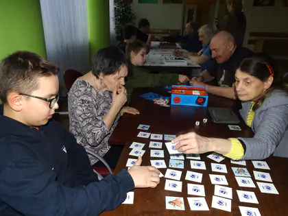 Chłopiec i mieszkańcy grają w grę z kartami ułożonymi na stole