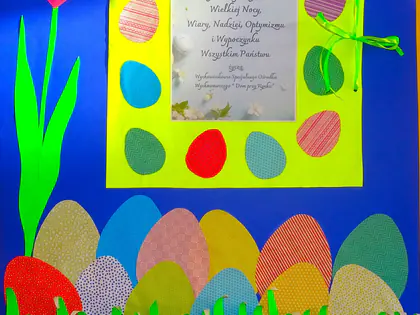 Wielkanocna plakietka z życzeniami, kolorowymi pisankami i tulipanem na niebieskim tle