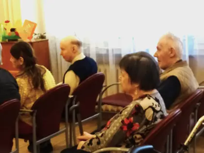Mieszkańcy siedzą w sali na krzesłach i słuchają prelekcji