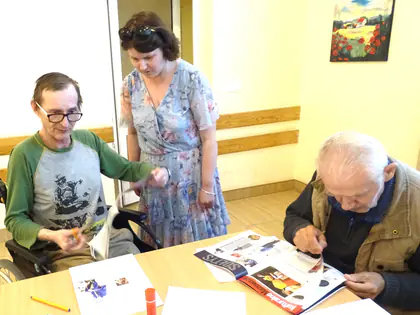 Kobieta i dwaj mężczyźni przy stole z gazetą i kartkami