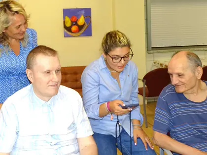Czworo osób siedzi obok siebie, jedna z kobiet trzyma telefon