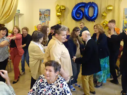 Goście tańczą pod dekoracją z niebieskim balonem 60 i złotymi gwiazdami