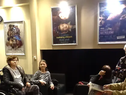 Mieszkańcy siedzą w holu kina pod plakatami filmowymi