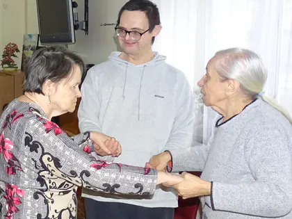 Dwie starsze kobiety tańczą w parze, obok stoi mężczyzna w okularach