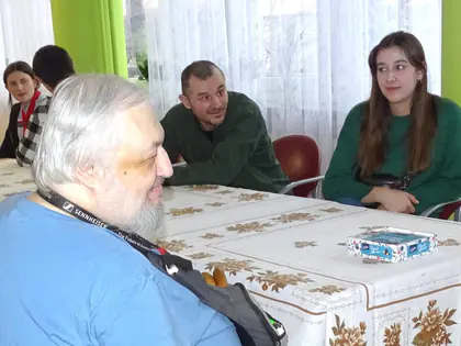 Skauci rozmawiają z mieszkańcami przy stole z gierką planszową