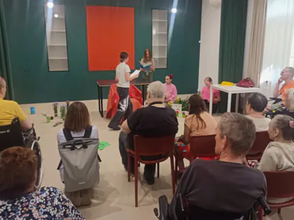 Mieszkańcy oglądają przedstawienie uczennic w świetlicy