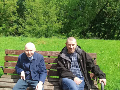 Dwaj mieszkańcy siedzą na ławce na trawie w parku