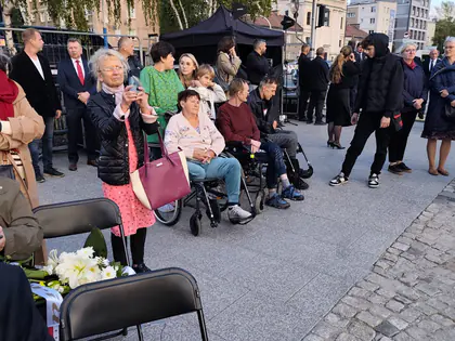 Mieszkańcy na wózkach wśród uczestników uroczystości na skwerze