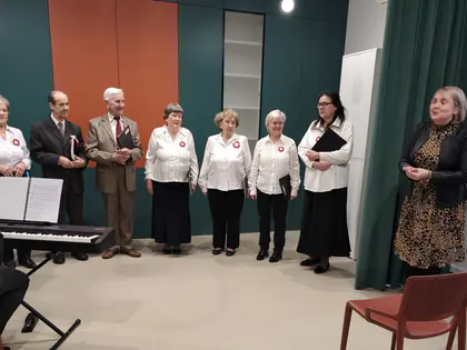 Zespół wokalny w białych bluzkach z kotylionami śpiewa przy keyboardzie
