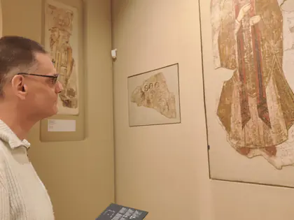 Mieszkaniec ogląda fragment fresku w muzeum