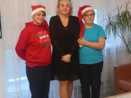 Trzy kobiety w czapkach mikołajkowych i z rogami renifera pozują do zdjęcia