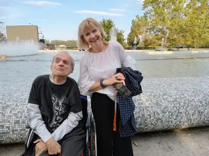 Mieszkaniec na wózku i opiekunka przy fontannie