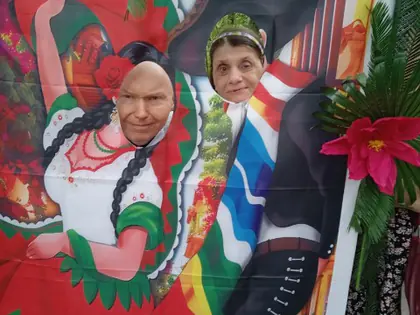 Dwoje mieszkańców pozuje w otworach ścianki z meksykańskimi tancerzami